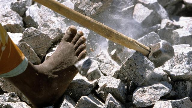 Barfüßig arbeitet ein Mitglied der Kaste der Unberührbaren in einem Steinbruch in Madurai (Indien).