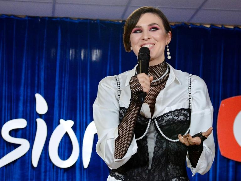Die ukrainische Sängerin Maruv. Sie steht mit einem Mikrofon in der Hand auf der Bühne und lächelt.