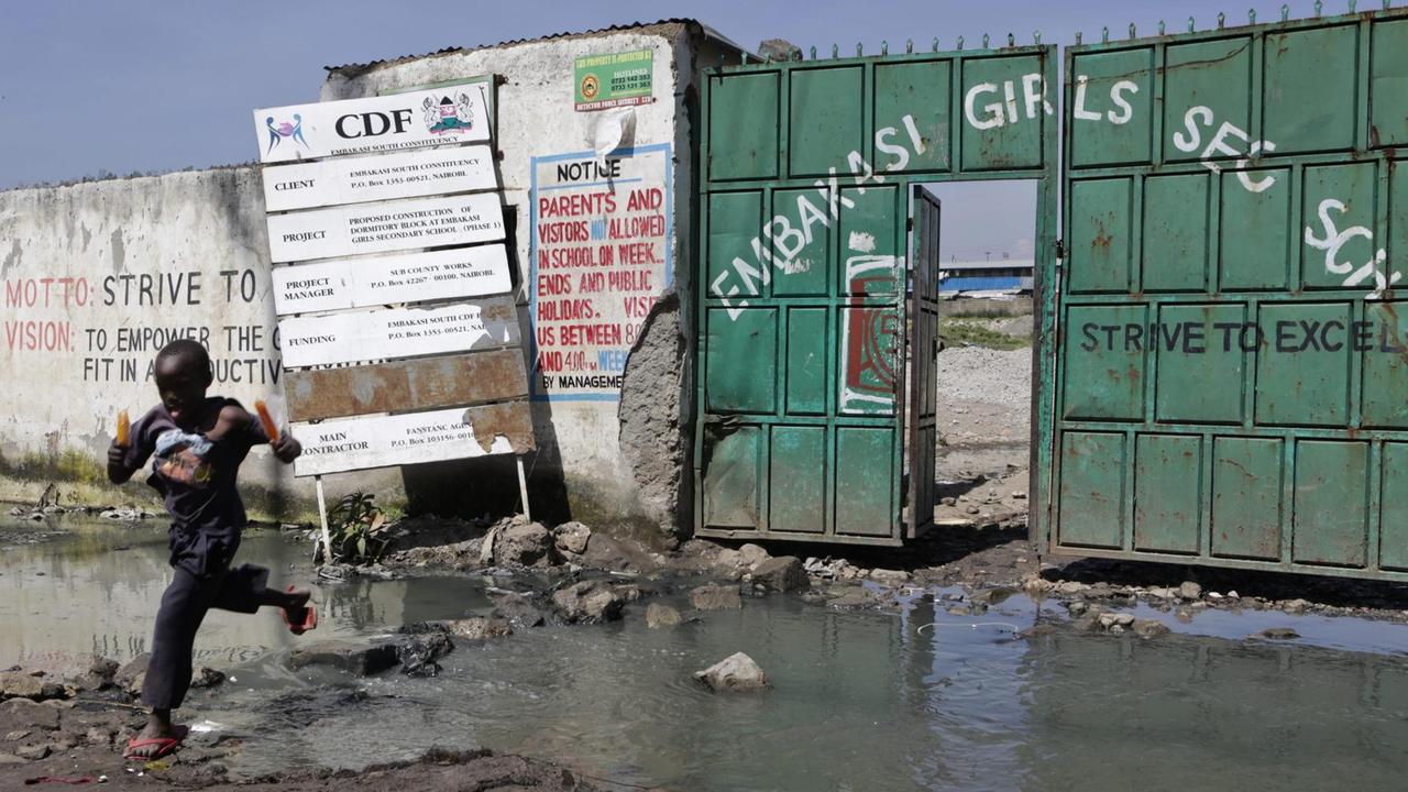 A young Kenyan boy jumps across a puddle of sewage water outside the main entrance gate of Embakasi Girls Secondary School a public school in the Mukuru kwa Njenga slums of Nairobi, Kenya, 15 December 2016. A young Kenyan boy jumps across a puddle of sewage water outside the main entrance gate of Embakasi Girls Secondary School a public school in the Mukuru kwa Njenga slums of Nairobi, Kenya, 15 December 2016.