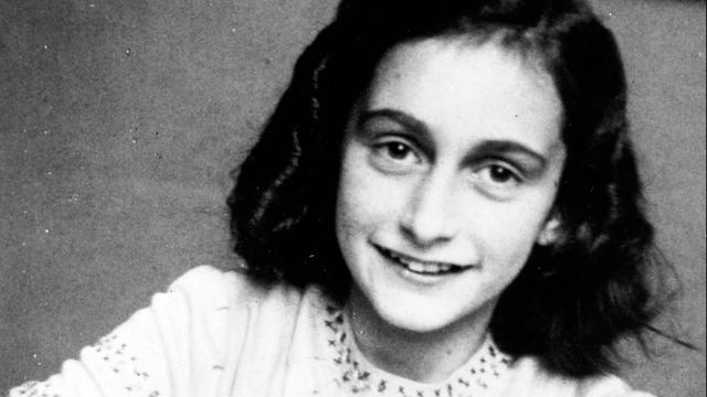 Es ist ein Schwarz-Weiß-Bild. Anne Frank lächelt im weißen Hemd in die Kamera. Ihre Haare sind dunkel. 