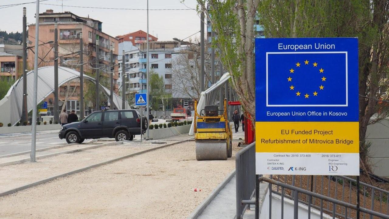 Auf der Brücke über den Fluss Ibar in der kosovarischen Stadt Mitrovica steht Baugerät und ein Schild, auf dem steht, dass die Sanierung ein EU-Projekt ist.
