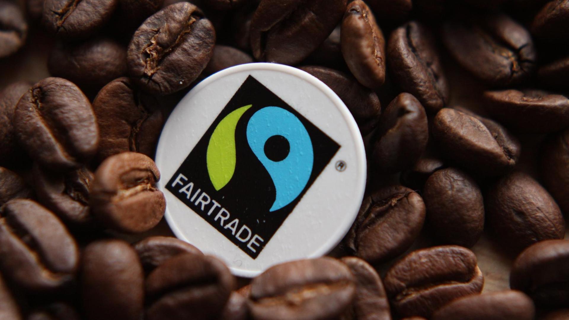 Fairtrade Siegel zwischen Kaffeebohnen Fairtrade Siegel zwischen Kaffeebohnen