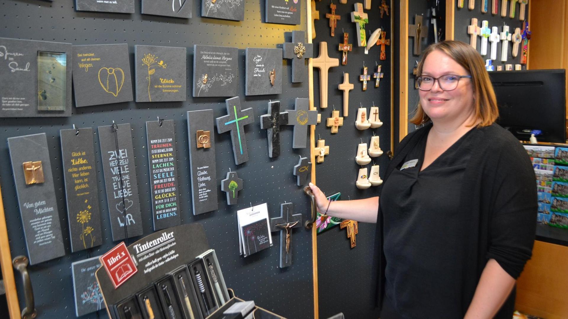 Verkäuferin Nina Bursche präsentiert im Aachener Domshop die Devotionalien, darunter eine bunte Auswahl von Kreuzen