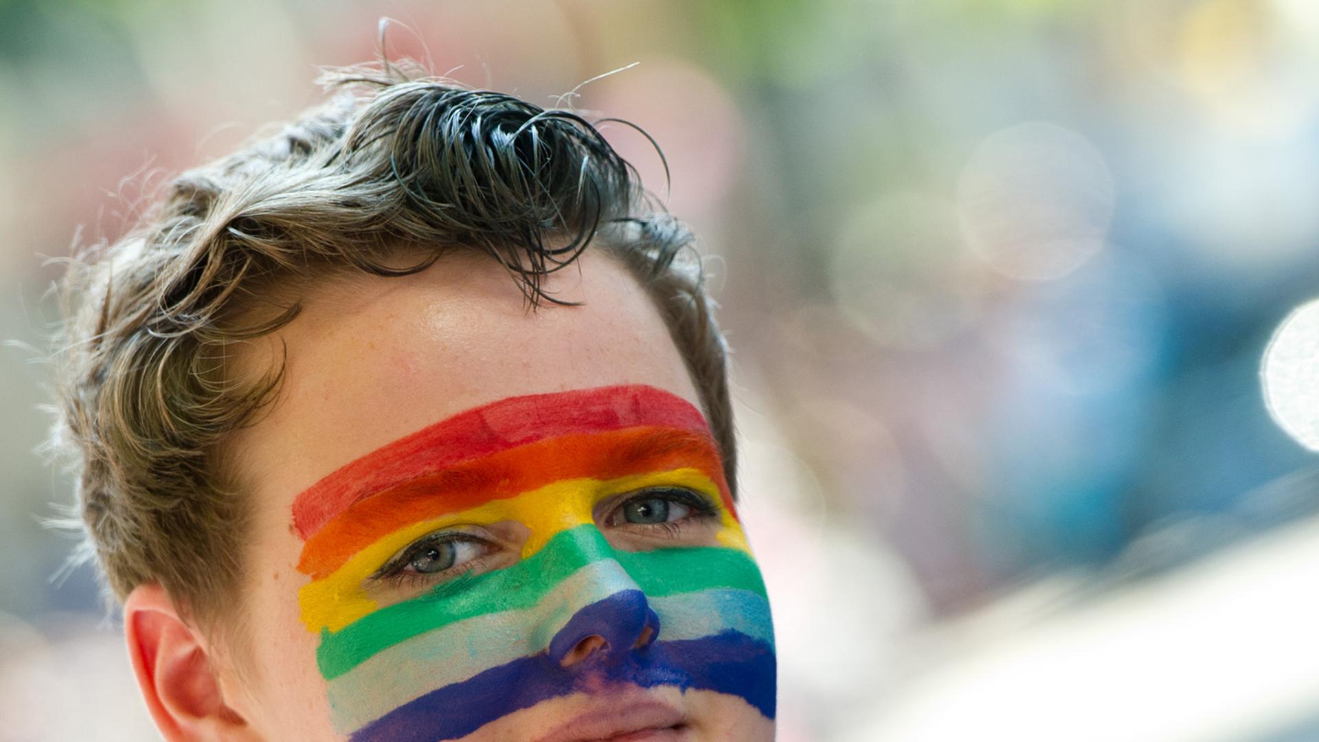 Eine Teilnehmerin des Christopher Street Day hat am 27.07.2013 in Stuttgart eine Regenbogenfahne auf ihr Gesicht gemalt. Eine Teilnehmerin des Christopher Street Day hat am 27.07.2013 in Stuttgart eine Regenbogenfahne auf ihr Gesicht gemalt.