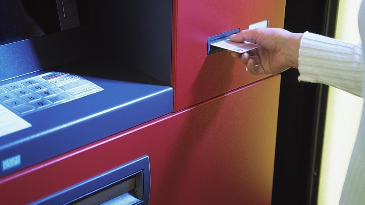 Eine Frau hebt Geld an einem Bankautomaten ab.