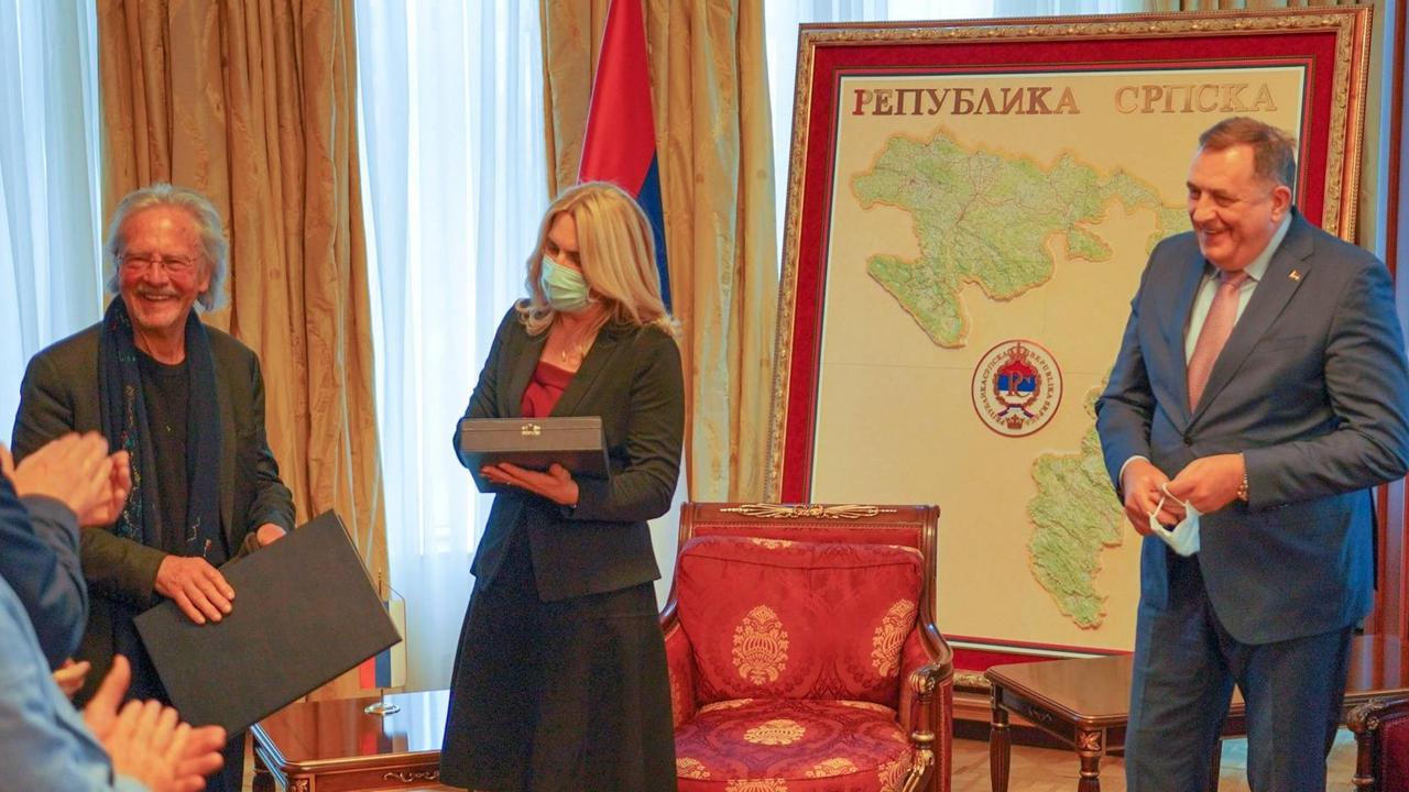 Peter Handke, Željka Cvijanović und Milorad Dodik (von links) stehen beisammen während Handke eine Ehrung überreicht bekommt. Peter Handke, Željka Cvijanović und Milorad Dodik (von links) stehen beisammen während Handke eine Ehrung überreicht bekommt.