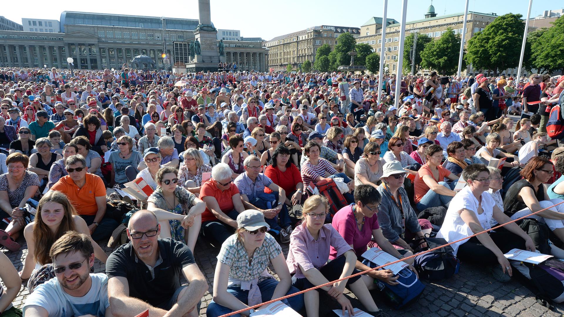 Teilnehmer des Eröffnungsgottesdienstes sitzen oder stehen am 03.06.2015 in Stuttgart (Baden-Württemberg) bei der Eröffnung des Evangelischen Kirchentags auf dem überfüllten Schlossplatz.