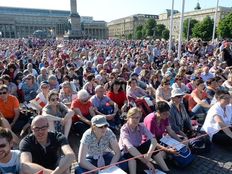 Teilnehmer des Eröffnungsgottesdienstes sitzen oder stehen am 03.06.2015 in Stuttgart (Baden-Württemberg) bei der Eröffnung des Evangelischen Kirchentags auf dem überfüllten Schlossplatz.