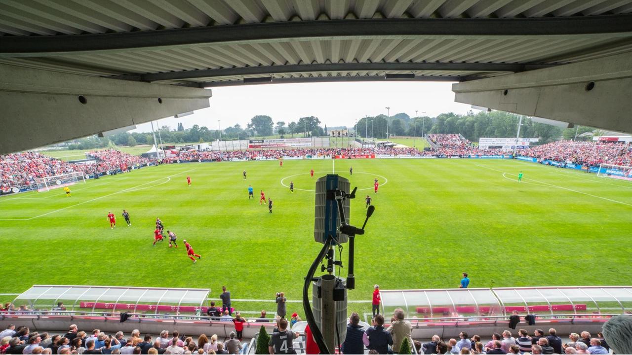 Ein runder Kasten hängt über der Tribüne mit Blick auf das Fußballfeld Ein runder Kasten hängt über der Tribüne mit Blick auf das Fußballfeld