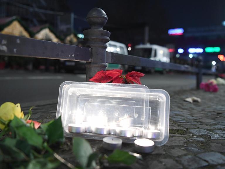 Blumen und Teelichter zum Gedenken an die Opfer stehen an einem Geländer vor dem Weihnachtsmarkt an der Gedächtniskirche in Berlin.