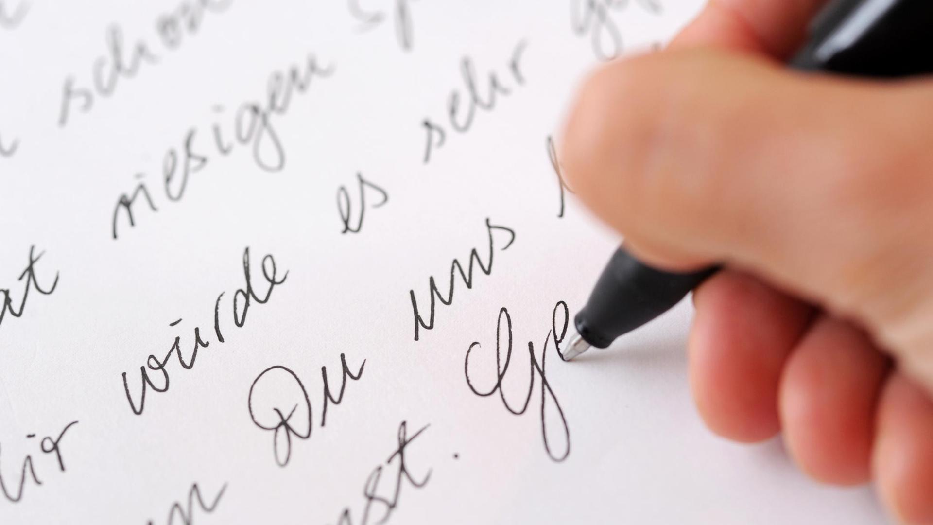 Eine Frau schreibt einen Brief mit einem Kugelschreiber.