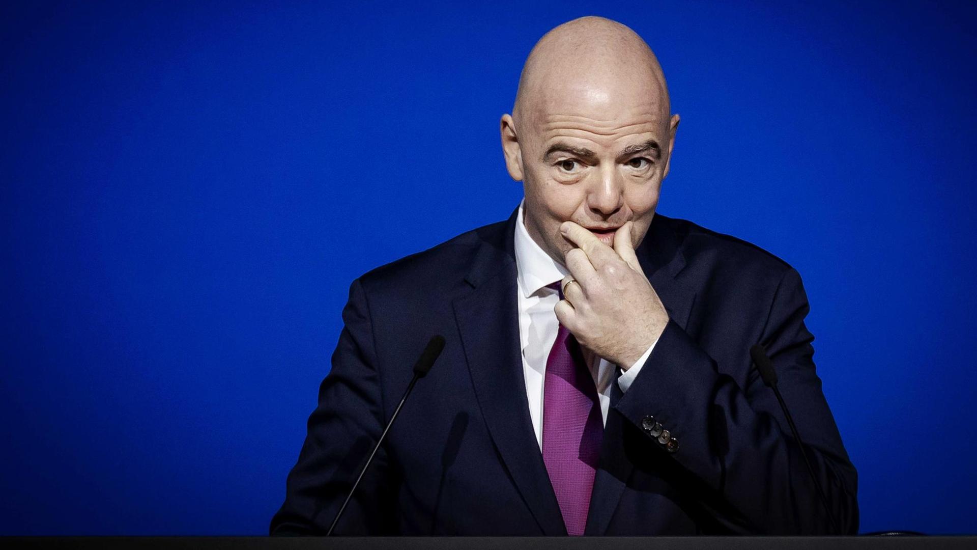 Portrait von FIFA-Präsidenten Gianni Infantino, der sich nachdenklich an den Mund fasst Portrait von FIFA-Präsidenten Gianni Infantino, der sich nachdenklich an den Mund fasst