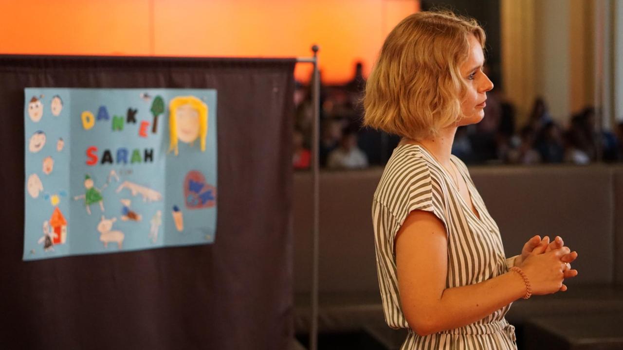 Sarah Görlitz vor einem selbst gemalten Bild von Kindern. Sarah Görlitz vor einem selbst gemalten Bild von Kindern.