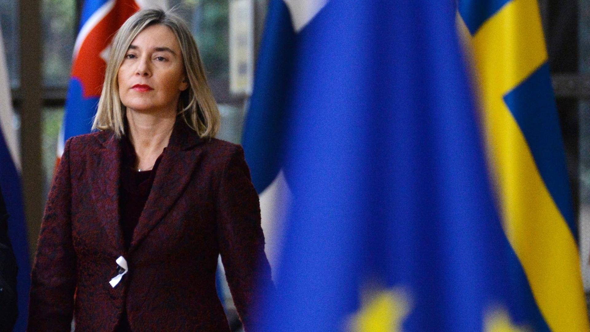 EU-Außenbeauftragte Mogherini mit ernstem Gesichtsausdruck, im Vordergrund schemenhaft die EU-Flagge EU-Außenbeauftragte Mogherini mit ernstem Gesichtsausdruck, im Vordergrund schemenhaft die EU-Flagge