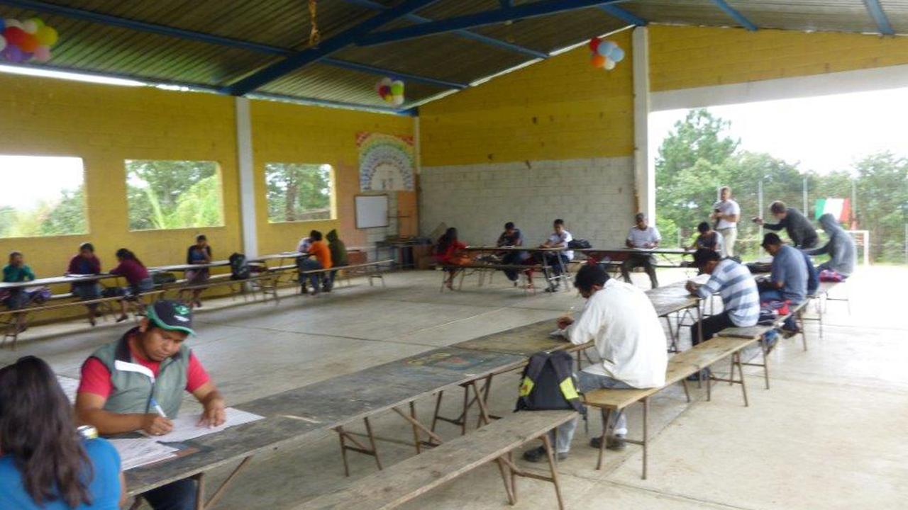Guatemaltekische Schüler sitzen unter einer Überdachung über Prüfungsaufgaben. Guatemaltekische Schüler sitzen unter einer Überdachung über Prüfungsaufgaben.