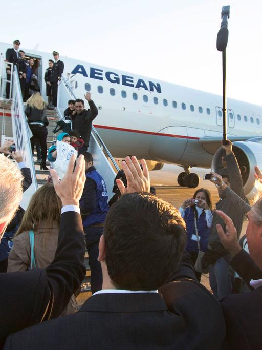 Die EU-Vertreter winken den Flüchtlingen auf dem Gateway am Flugzeug zu.
