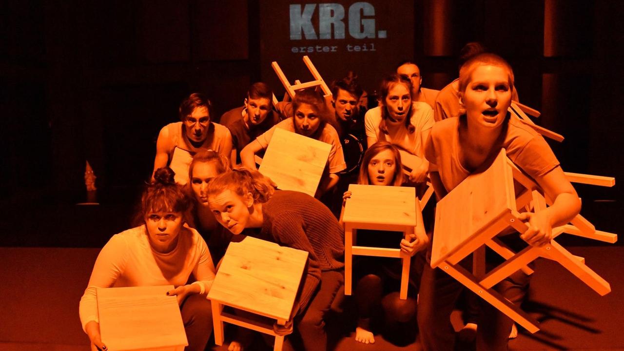 Jugendliche mit Stühlen in den Händen auf der Bühne Jugendliche mit Stühlen in den Händen auf der Bühne