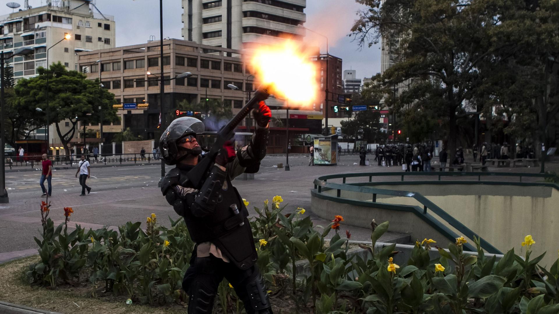 Ein Mitglied der venezolanischen Nationalpolizei schießt einen Tränengaskanister mit einem Gewehr ab, um regierungskritische Demonstranten zu vertreiben. Ein Mitglied der venezolanischen Nationalpolizei schießt einen Tränengaskanister mit einem Gewehr ab, um regierungskritische Demonstranten zu vertreiben.