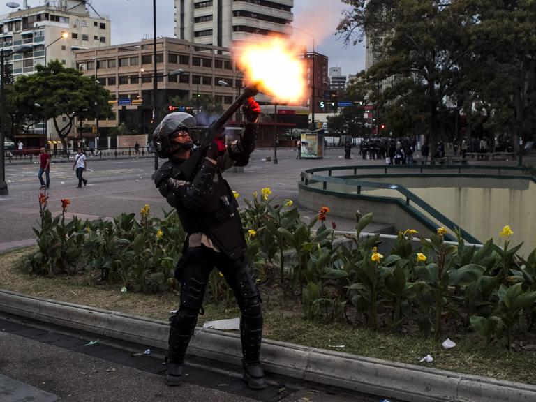 Ein Mitglied der venezolanischen Nationalpolizei schießt einen Tränengaskanister mit einem Gewehr ab, um regierungskritische Demonstranten zu vertreiben.