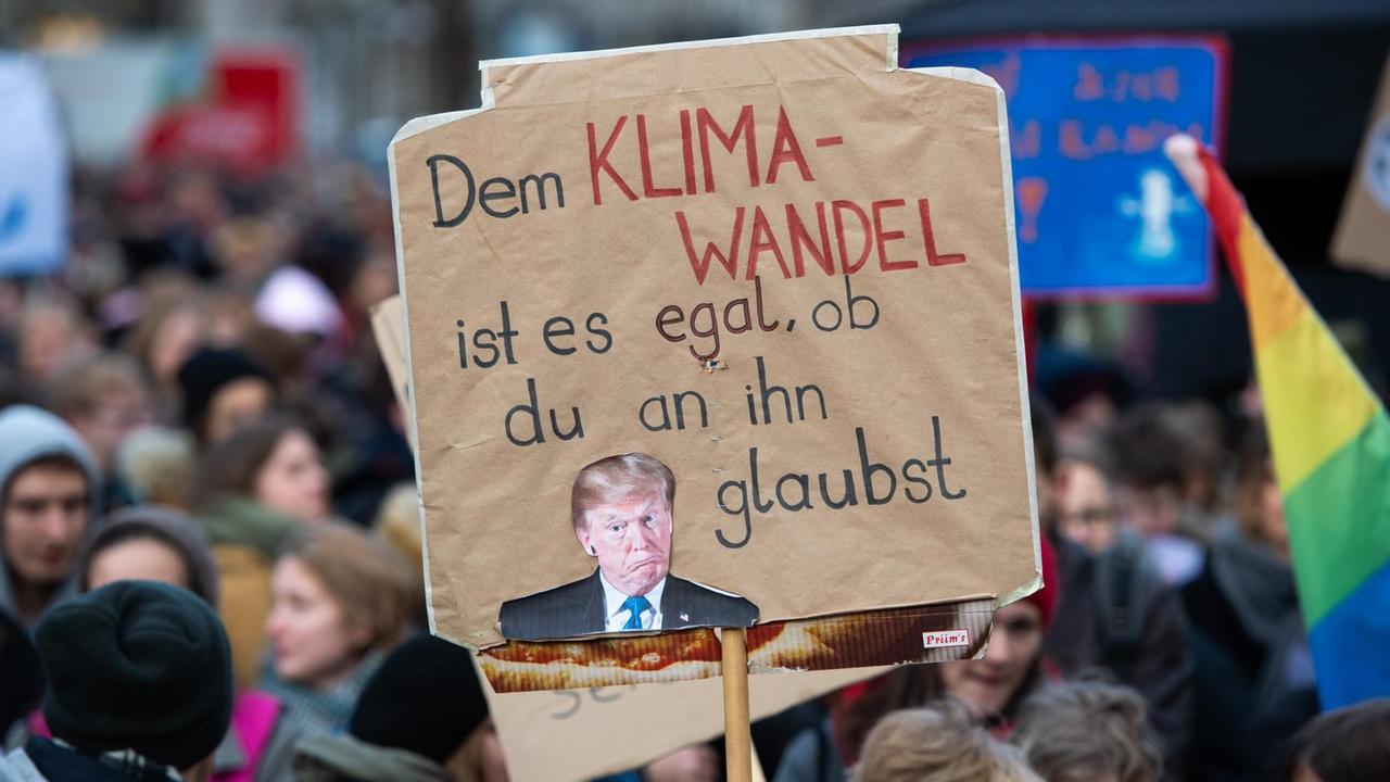 Ein Demonstrant hält ein Plakat mit der Aufschrift "Dem Klimawandel ist es egal, ob du an ihn glaubst" mit einem Foto von US-Präsident Trump bei einer Kundgebung von Fridays For Future zum globalen Aktionstag für mehr Klimaschutz. Ein Demonstrant hält ein Plakat mit der Aufschrift "Dem Klimawandel ist es egal, ob du an ihn glaubst" mit einem Foto von US-Präsident Trump bei einer Kundgebung von Fridays For Future zum globalen Aktionstag für mehr Klimaschutz.