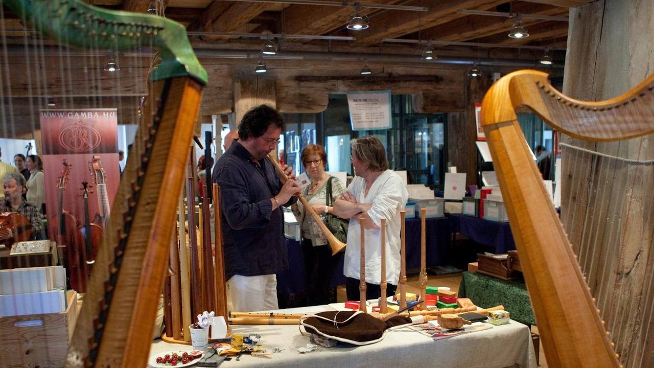 Ein Mann hat ein blockflötenartiges Instrument in der Hand und probiert es aus. Ein Mann hat ein blockflötenartiges Instrument in der Hand und probiert es aus.