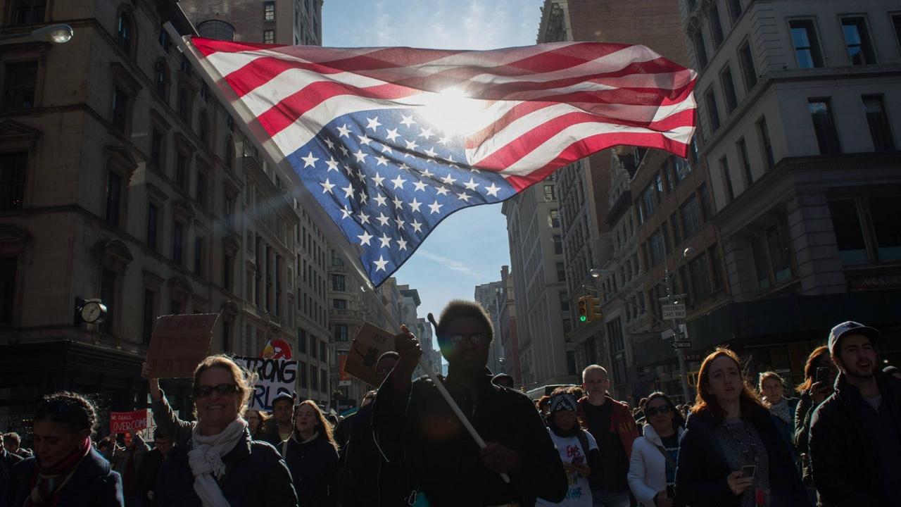 Ein Demonstrant hält eine auf dem Kopf stehende US-Flagge während einer Demonstration Ein Demonstrant hält eine auf dem Kopf stehende US-Flagge während einer Demonstration