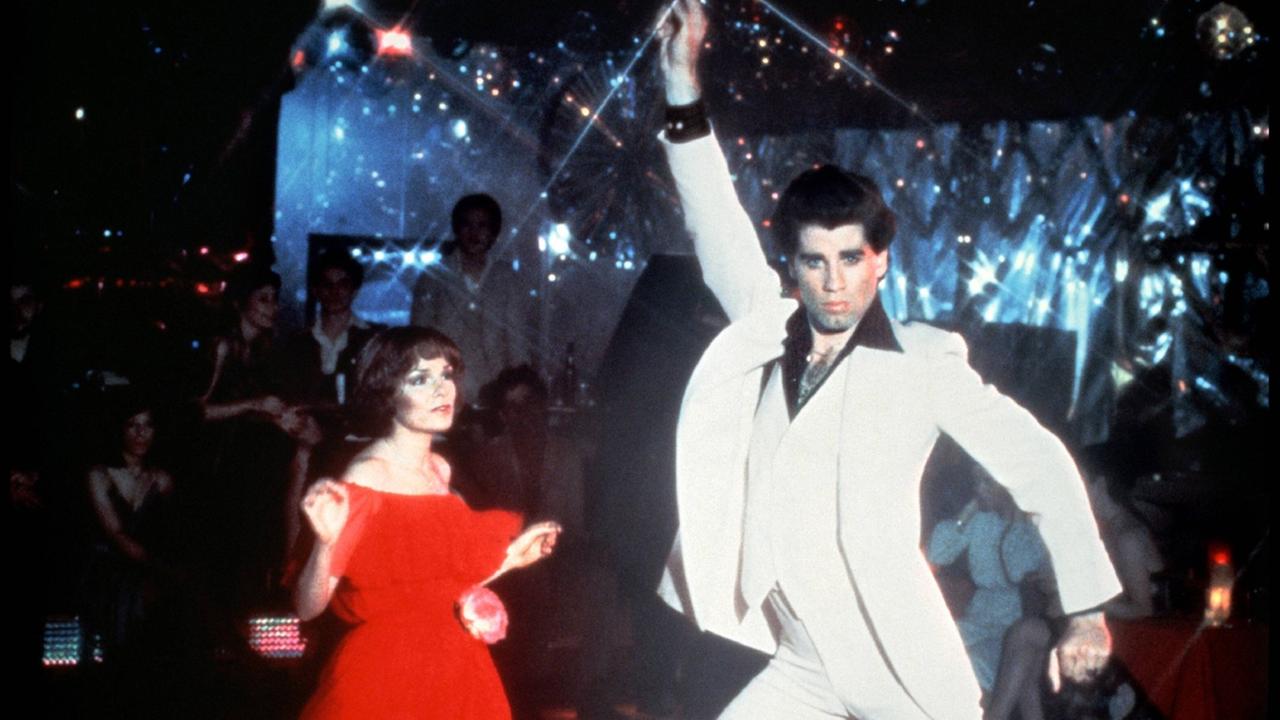 Karen Lynn Gorney und John Travolta in einer Szene aus "Saturday Night Fever", beide tanzen in einer Disco, John Travolta reckt den rechten Arm in die Höhe und biegt die Hüfte durch. Karen Lynn Gorney und John Travolta in einer Szene aus "Saturday Night Fever", beide tanzen in einer Disco, John Travolta reckt den rechten Arm in die Höhe und biegt die Hüfte durch.