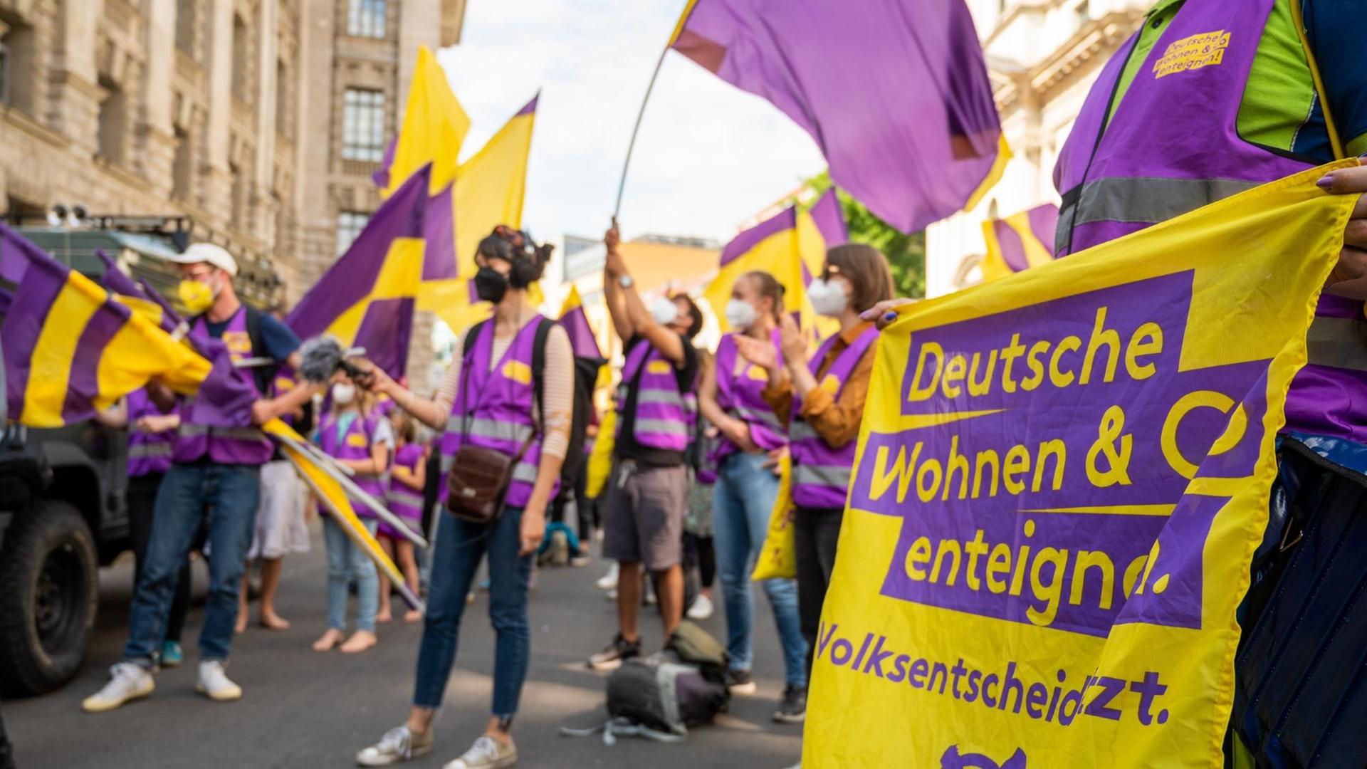 Unterstützer der Initiative "Deutsche Wohnen & Co. enteignen" schwenken bei der Übergabe der gesammelten Unterschriften für einen Volksentscheid zur Enteignung von großen Immobilienunternehmen vor der Senatsverwaltung für Inneres und Sport Fahnen. Unterstützer der Initiative "Deutsche Wohnen & Co. enteignen" schwenken bei der Übergabe der gesammelten Unterschriften für einen Volksentscheid zur Enteignung von großen Immobilienunternehmen vor der Senatsverwaltung für Inneres und Sport Fahnen.