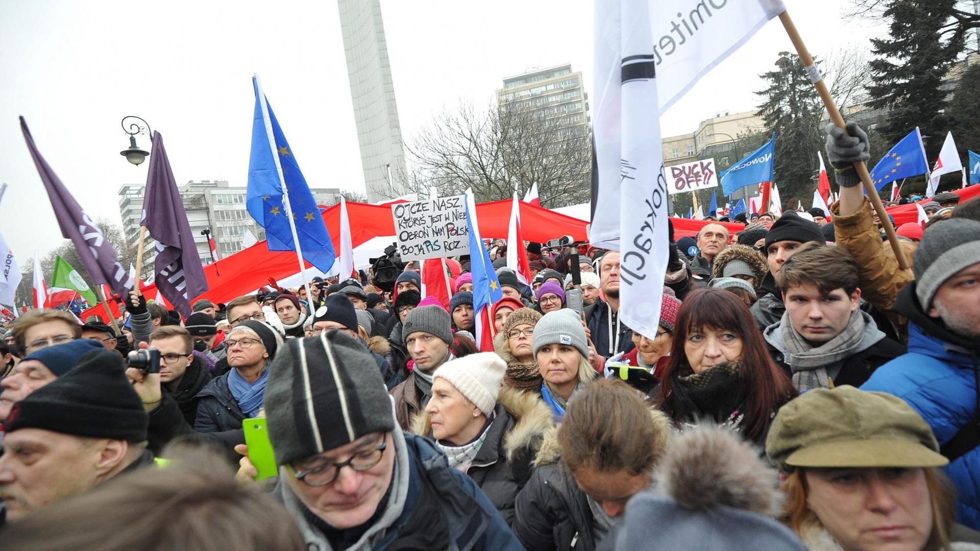 Eine Menschenmenge vor dem Parlamentsgebäude in Warschau hält Banner und Fahnen in die Höhe. Eine Menschenmenge vor dem Parlamentsgebäude in Warschau hält Banner und Fahnen in die Höhe.