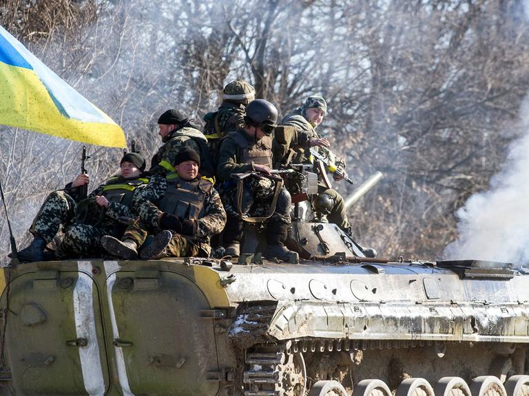 Ein Panzer mit ukrainischer Fahne und Soldaten 