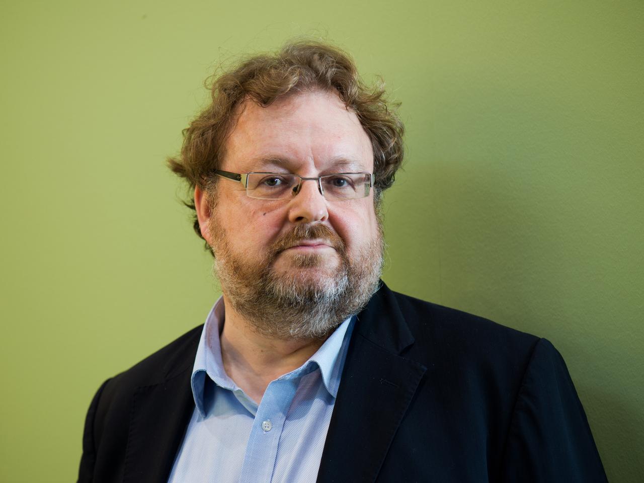Der FAZ-Redakteur Jürgen Kaube, Man mit Brille und vor grüner Wand, in die Kamera blickend. Der FAZ-Redakteur Jürgen Kaube, Man mit Brille und vor grüner Wand, in die Kamera blickend.