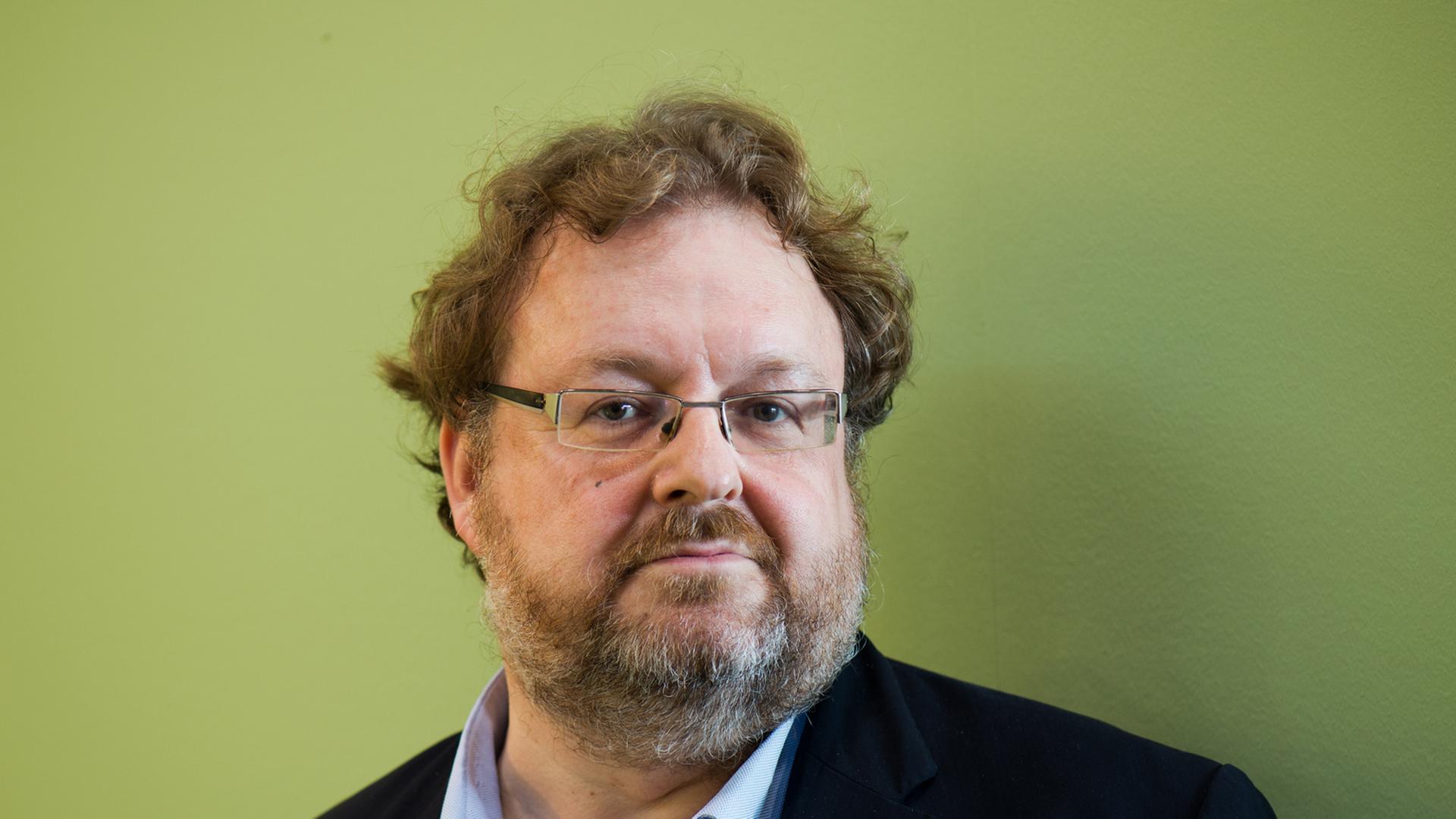 Der FAZ-Redakteur Jürgen Kaube, Man mit Brille und vor grüner Wand, in die Kamera blickend. Der FAZ-Redakteur Jürgen Kaube, Man mit Brille und vor grüner Wand, in die Kamera blickend.