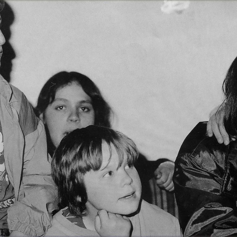 Ein altes Schwarz-Weiß-Foto zeigt Kinderheimleiterin Sibylle Hüttemann mit Straßenkindern am Bukarester Nordbahnhof.
