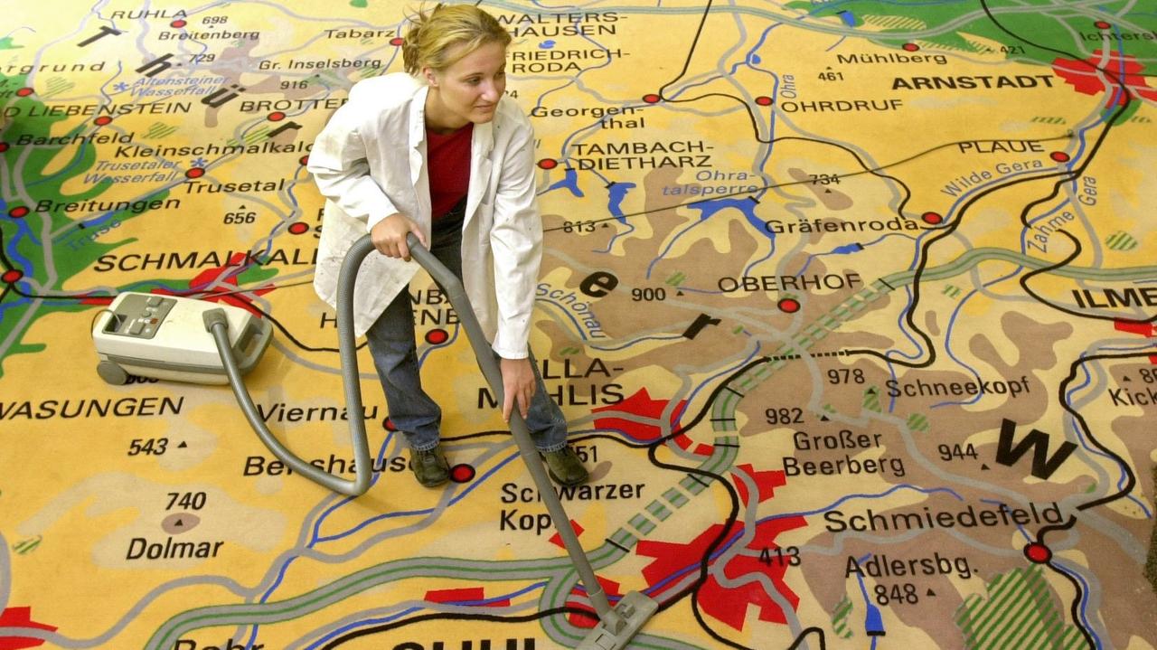 Eine acht mal acht Meter große Landkarte des Thüringer Waldes wird in Gotha von einer jungen Frau mit dem Staubsauger gereinigt. Der Karten-Teppich ist Teil der Ausstellung "Thüringer Wald - Natur in Szene gesetzt"