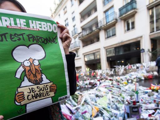 Eine Frau zeigt die erste Ausgabe des Satiremagazins "Charlie Hebdo" nach den Anschlägen von Paris.