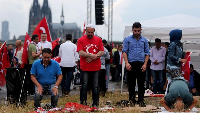 Anhänger des türkischen Staatspräsidenten Erdogan beten am 31.07.2016 in Köln (Nordrhein-Westfalen) vor der Kundgebung