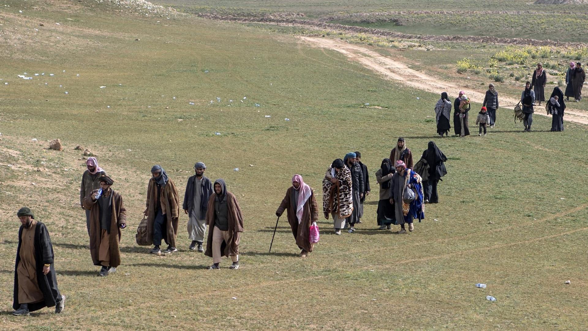 Mutmaßliche IS-Kämpfer verlassen mit ihren Angehörigen den umkämpften Ort Baghouz