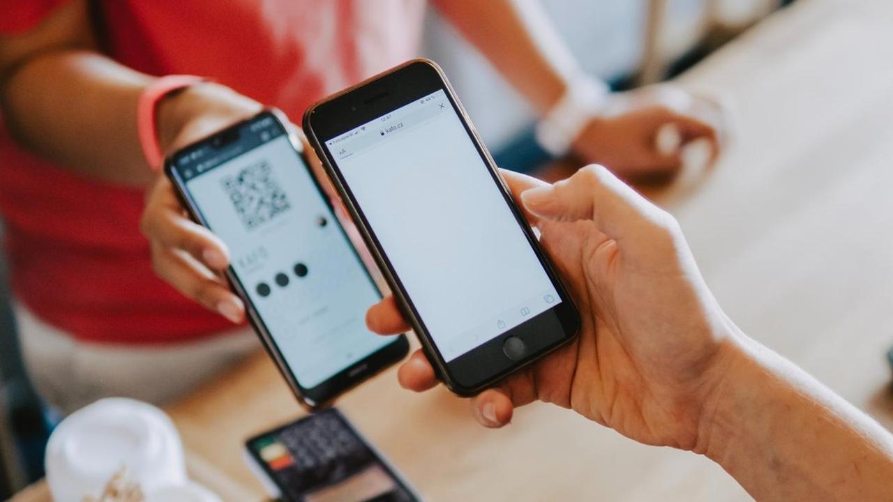 Zwei Personen halten zwei Smartphones übereinander. Das eine liest den QR-Code des anderen ein. Zwei Personen halten zwei Smartphones übereinander. Das eine liest den QR-Code des anderen ein.