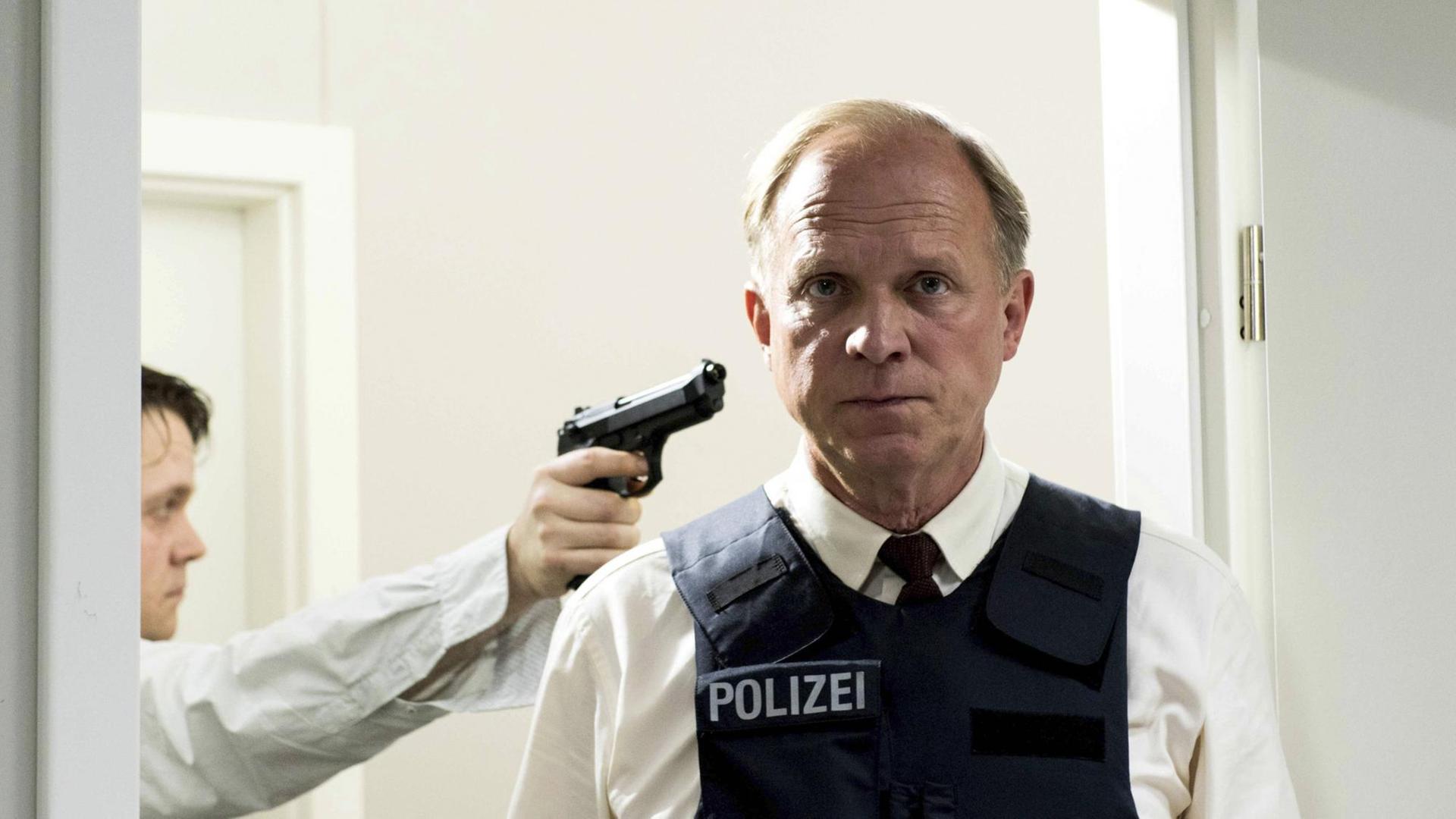 Ein Mann hält eine Pistole an den Kopf des LKA-Ermittlers Felix Murot, der gleichgültig in die Kamera schaut. Ein Mann hält eine Pistole an den Kopf des LKA-Ermittlers Felix Murot, der gleichgültig in die Kamera schaut.