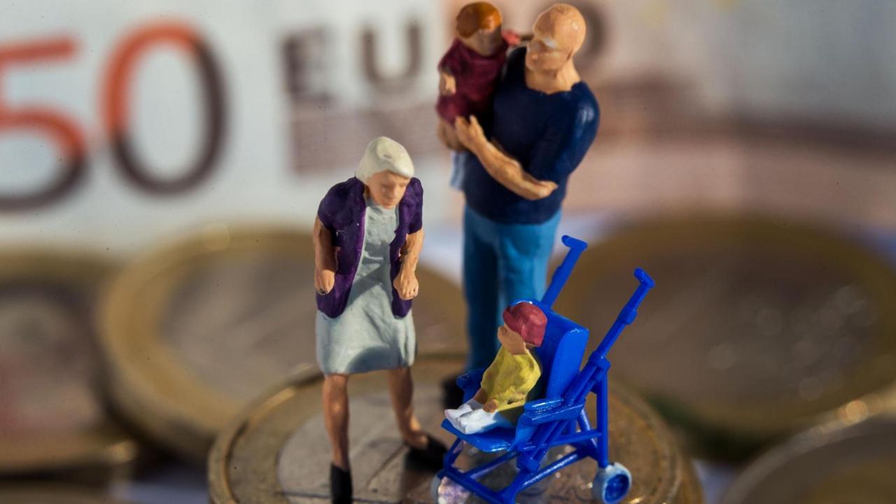 Das Bild zeigt Miniaturfiguren (Mutter, Vater mit Kind im Arm, ein weiteres Kind im Buggy) auf einem Stapel von Euro-Geldmünzen. Im Hintergrund sieht man unscharf einen 50-Euro-Schein. Das Bild zeigt Miniaturfiguren (Mutter, Vater mit Kind im Arm, ein weiteres Kind im Buggy) auf einem Stapel von Euro-Geldmünzen. Im Hintergrund sieht man unscharf einen 50-Euro-Schein.