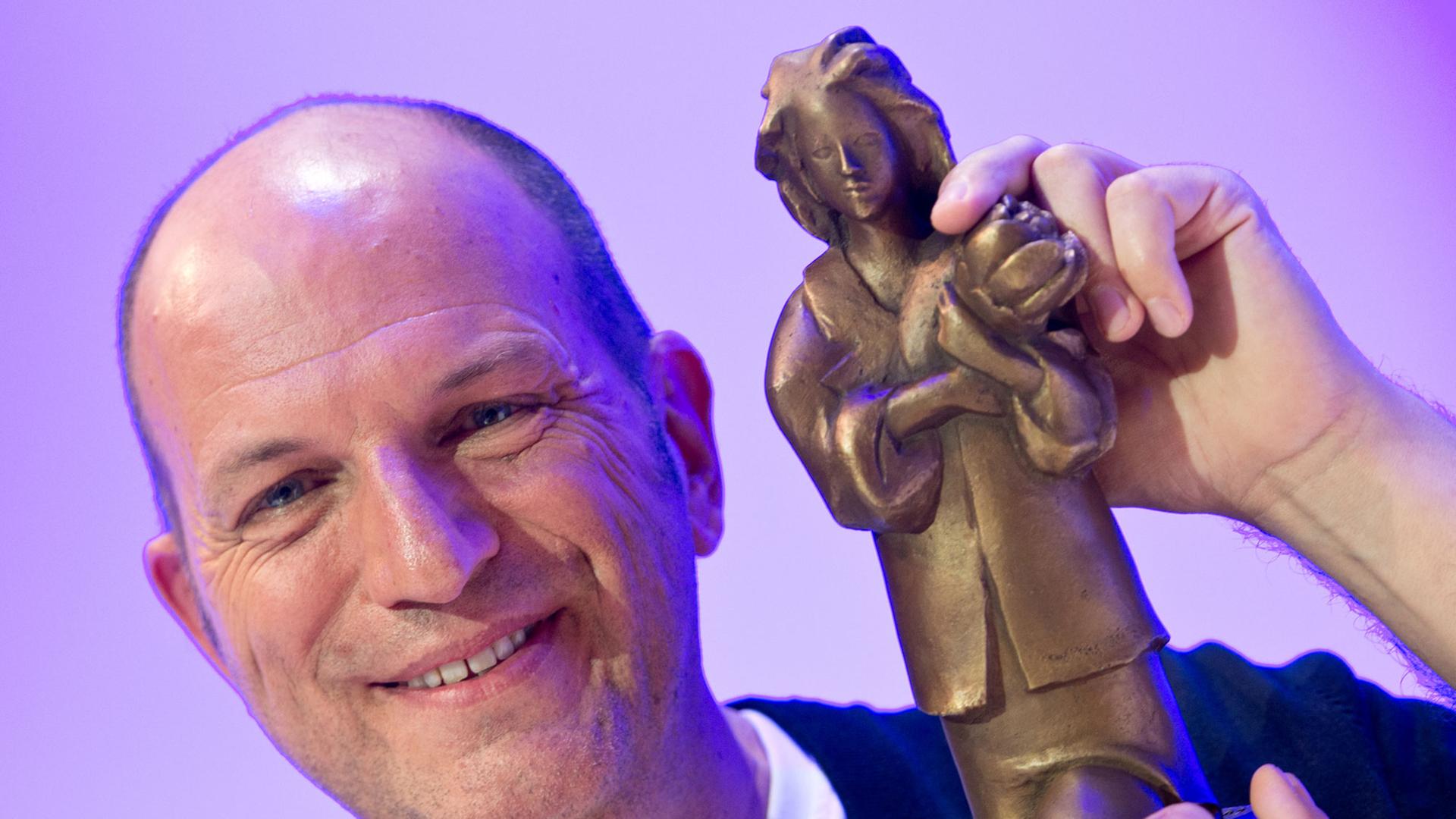 Der Autor Andreas Steinhöfel hält am 11.10.2013 auf der Buchmesse in Frankfurt am Main bei der Verleihung des Deutschen Jugendliteraturpreises 2013 seine Trophäe hoch. Der Autor Andreas Steinhöfel hält am 11.10.2013 auf der Buchmesse in Frankfurt am Main bei der Verleihung des Deutschen Jugendliteraturpreises 2013 seine Trophäe hoch.