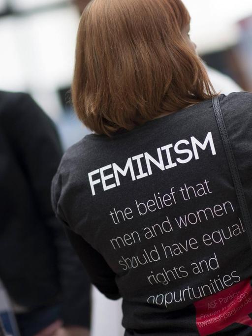 Frau mit schwarzem T-Shirt und Aufdruck "Feminism"