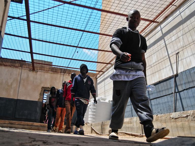 Afrikanische Geflüchtete gehen am 05.04.2017 in einem Flüchtlingslager in Tripolis (Libyen) vom Sport zurück in ihre Unterkunft.