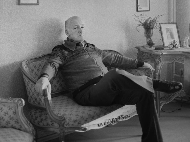 Der Pianist Swjatoslaw Richter sitzt in einem Wohnzimmer auf einer Couch.
