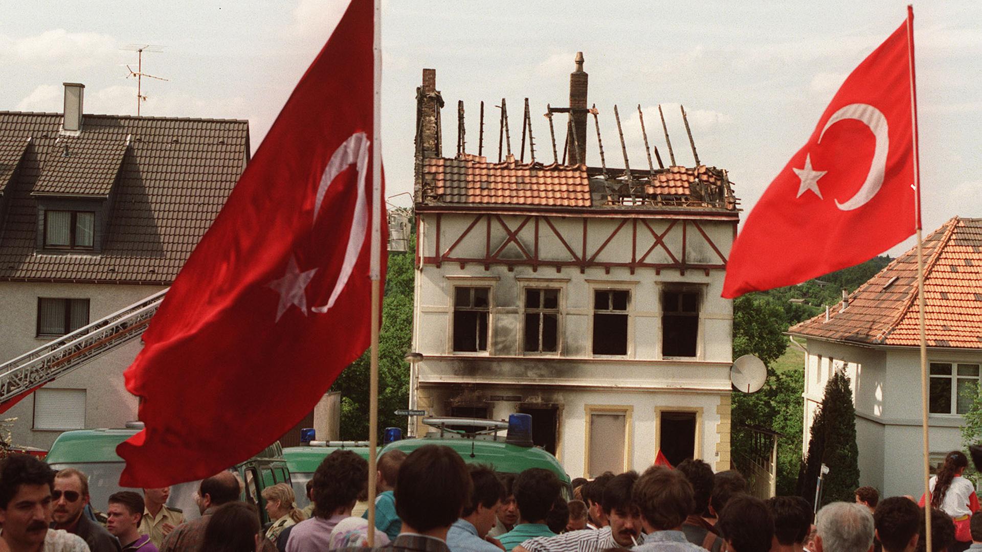 Demonstranten tragen am 29. Mai 1993 vor dem ausgebrannten Haus in Solingen türkische Fahnen. Demonstranten tragen am 29. Mai 1993 vor dem ausgebrannten Haus in Solingen türkische Fahnen.
