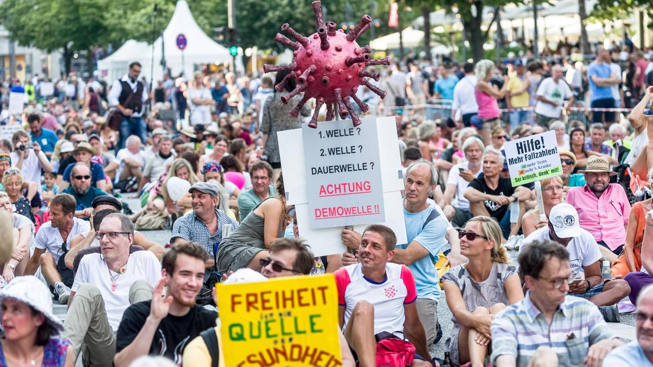 Ein Mann hält in Hamburg das Modell eines Corona-Virus mit einem Plakat mit der Aufschrift "Stoppt den Corona-Wahnsinn!" bei einer Kundgebung von Gegner der Coronaschutzmaßnahmen. Ein Mann hält in Hamburg das Modell eines Corona-Virus mit einem Plakat mit der Aufschrift "Stoppt den Corona-Wahnsinn!" bei einer Kundgebung von Gegner der Coronaschutzmaßnahmen.