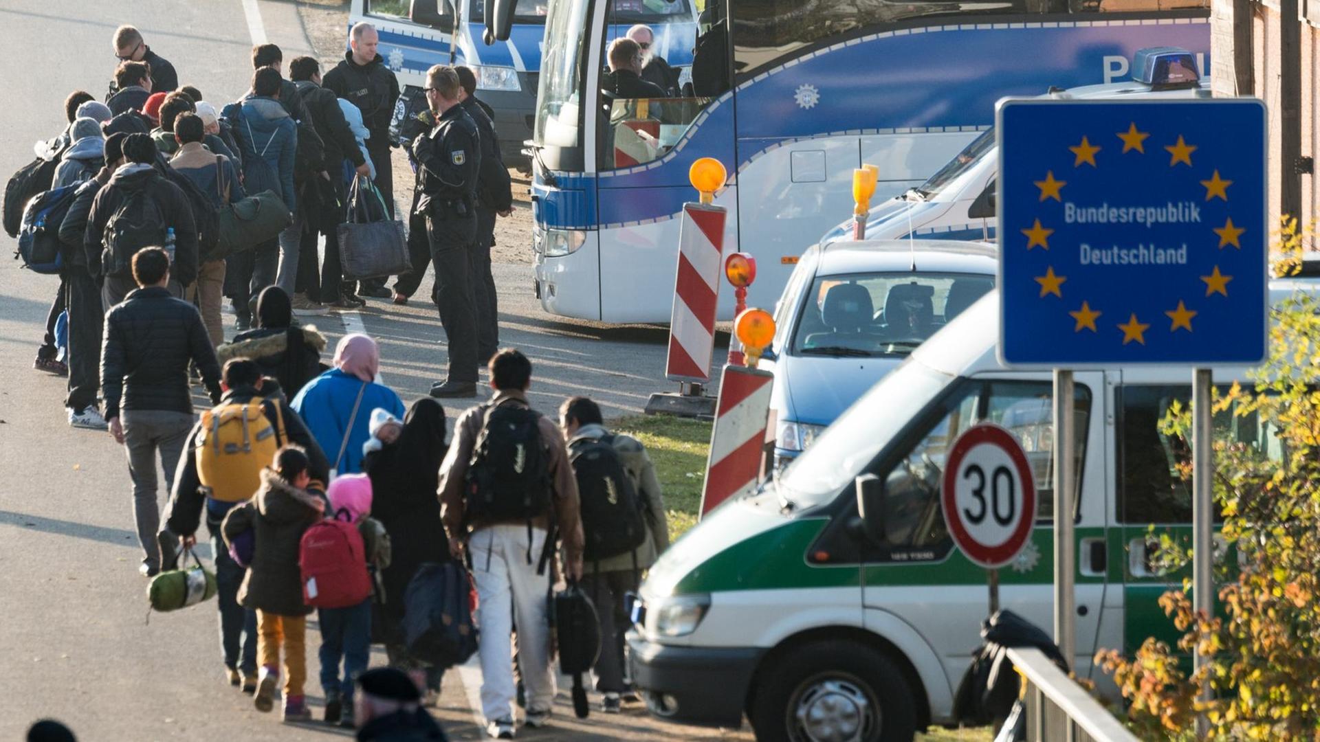 Beamte der Bundespolizei führen am 30.10.2015 an der deutsch-österreichischen Grenze nahe Wegscheid (Bayern) Flüchtlinge zu Bussen.