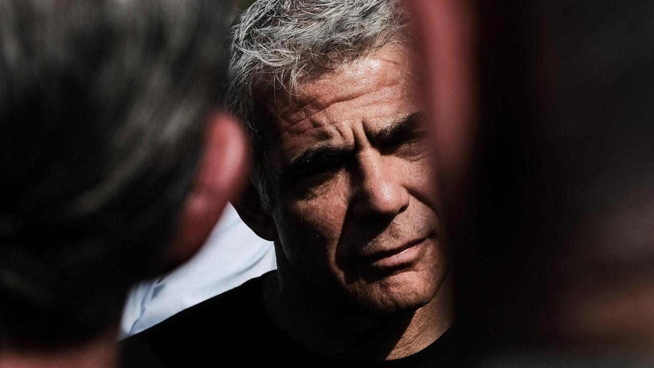 Jair Lapid in Nahaufnahme mit ernstem Gesichtsausdruck, umringt von Menschen.