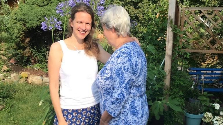 Die Journalistin mit ihrer Mutter, die an Alzheimer erkrankt ist. Die beiden stehen in einem Garten auf einer Terrasse.