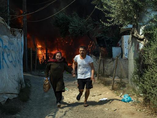 Ein rennedes Paar flieht vor den Flammen und dem Feuer, das im Flüchtlingslager Moria ausgebrochen ist.